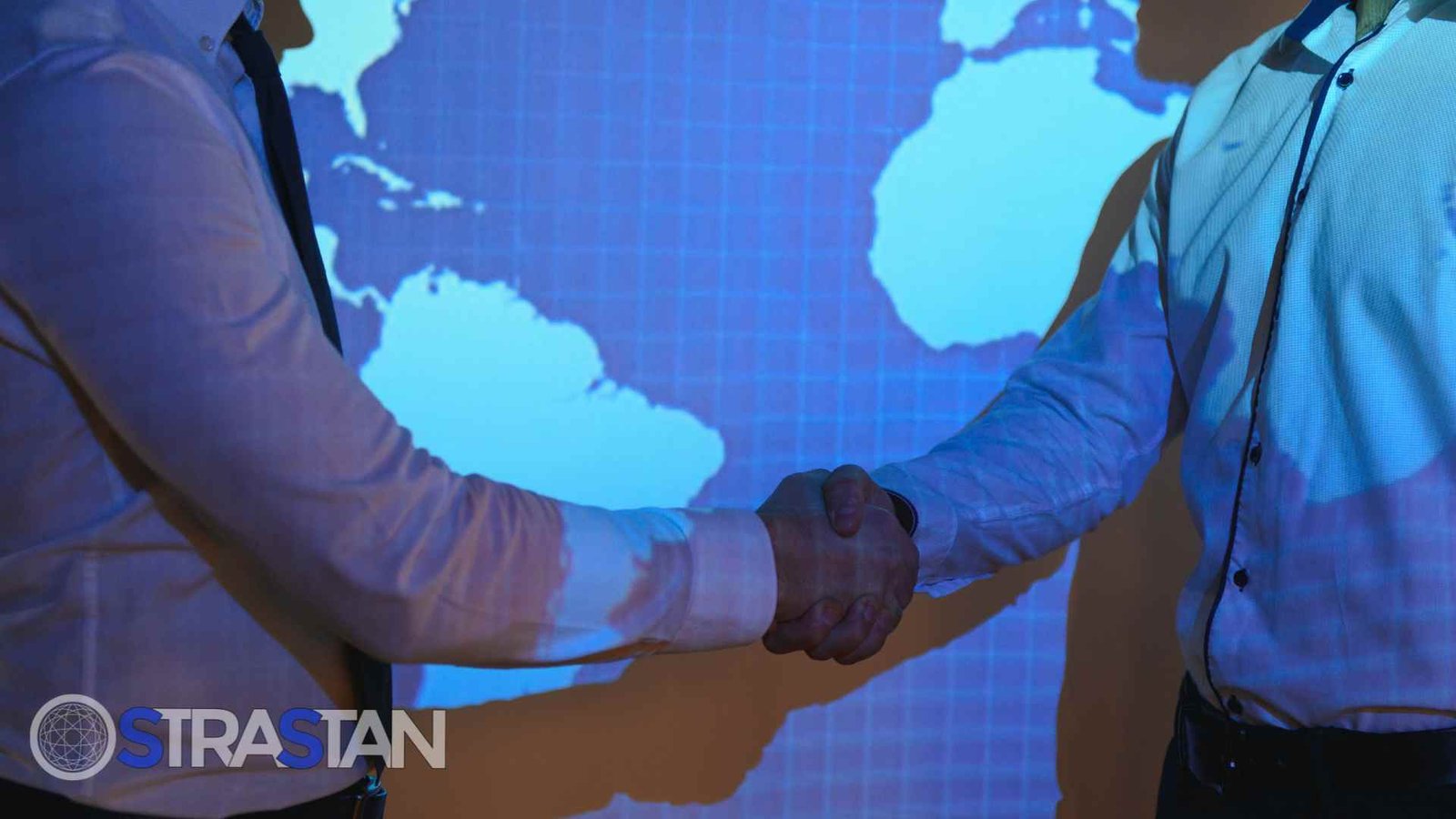 Two business partners shaking hands in front of a world map, representing a global tech partnership built on the principle of thinking a decade forward.
