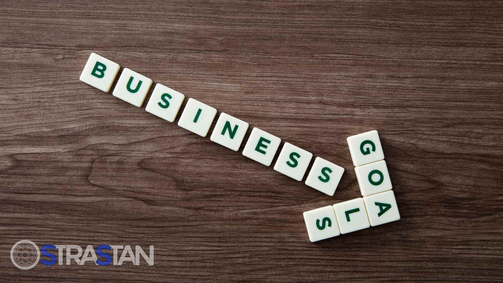 Tiles spelling out 'Business Goals' on a wooden table, representing the importance of aligning on long-term objectives when thinking a decade forward.
