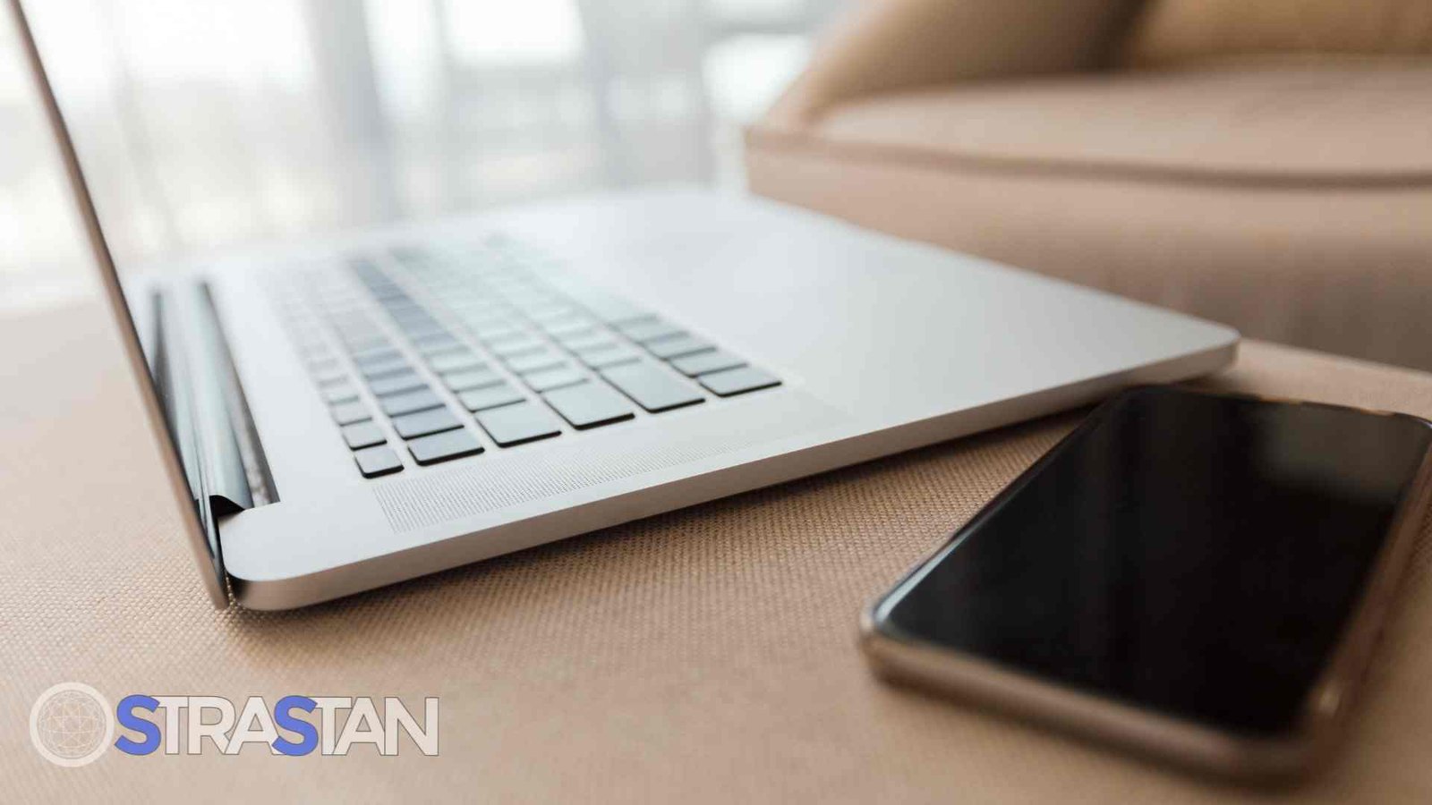 A side view of a laptop next to a smartphone, a classic representation of the devices central to the debate of mobile vs web apps.