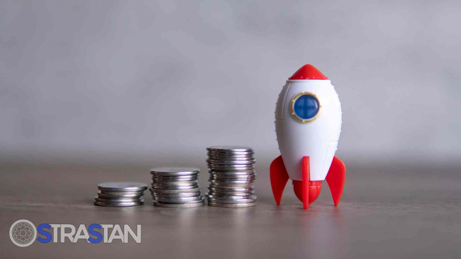 Stacks of coins next to a toy rocket, symbolizing financial growth and successful budget planning.