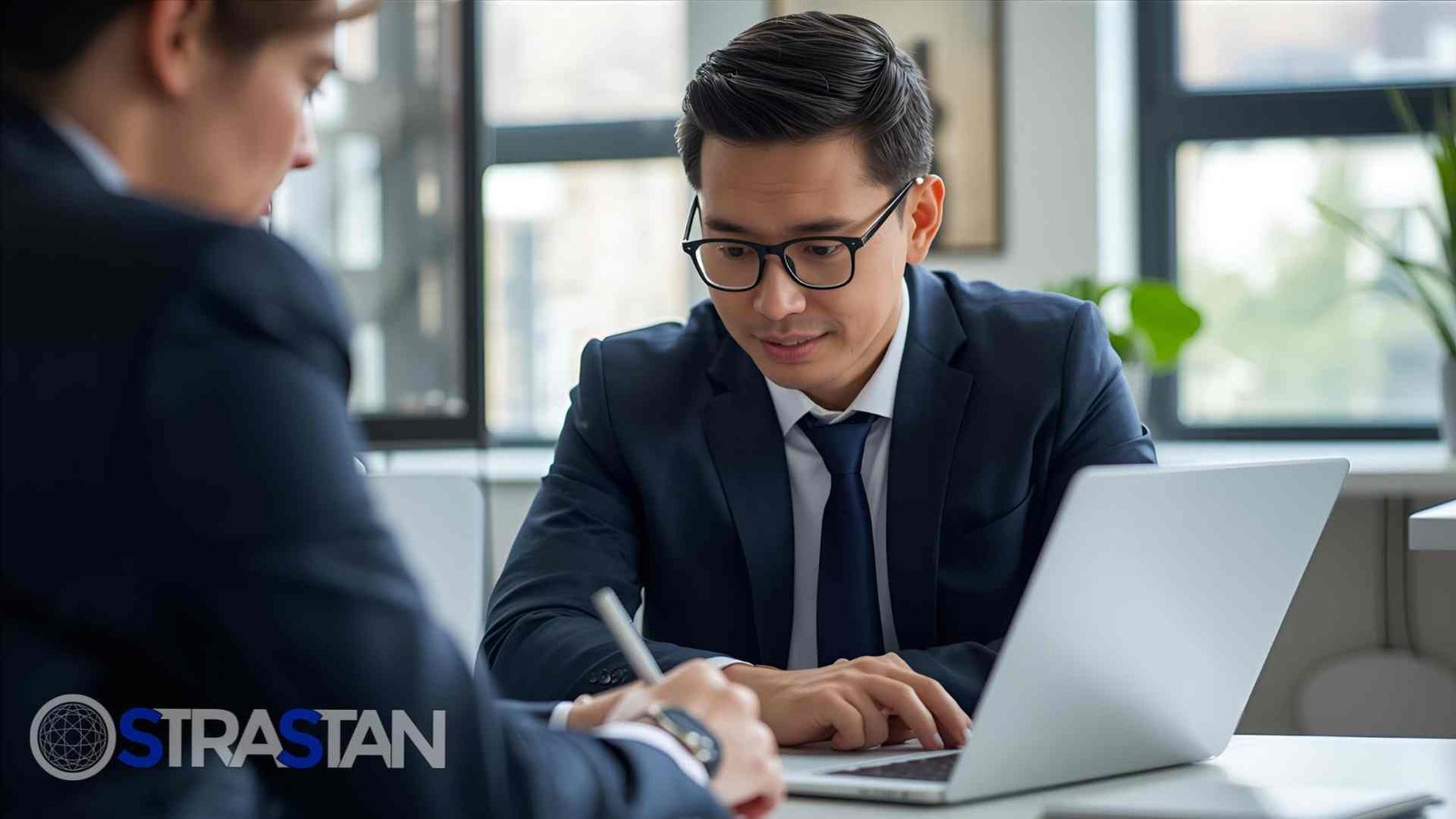 A male professional focused on a laptop screen during a meeting, representing the technical assessment phase of dev hiring.