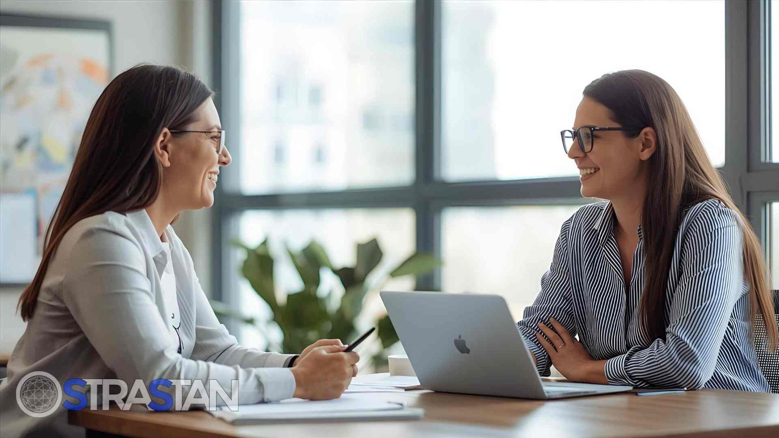 Two women smiling and collaborating during a meeting, representing a successful and positive interview experience in dev hiring.