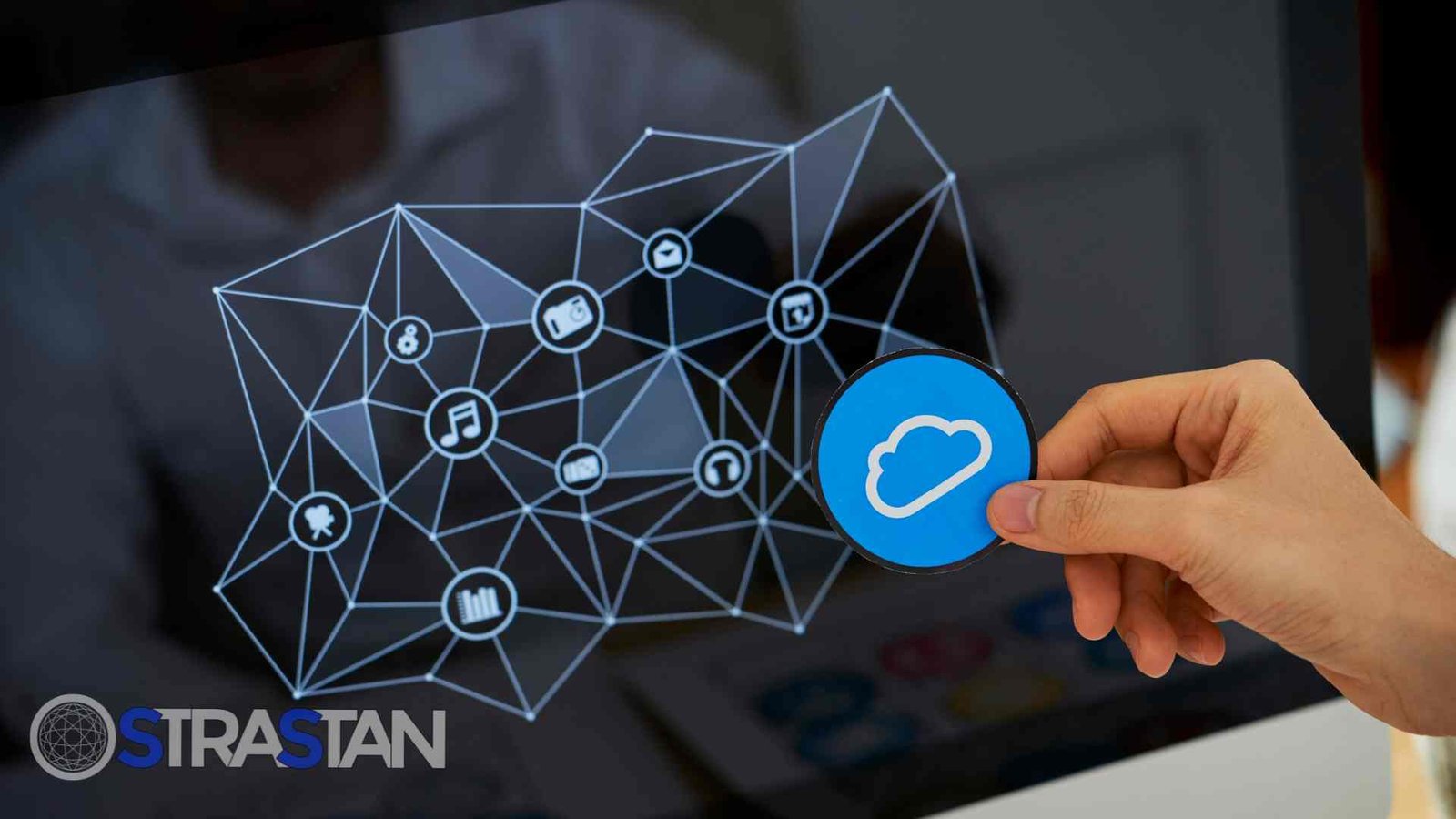 A hand holding a blue cloud icon in front of a screen with a network diagram, illustrating the critical role of cloud computing tools 2025 in web development.