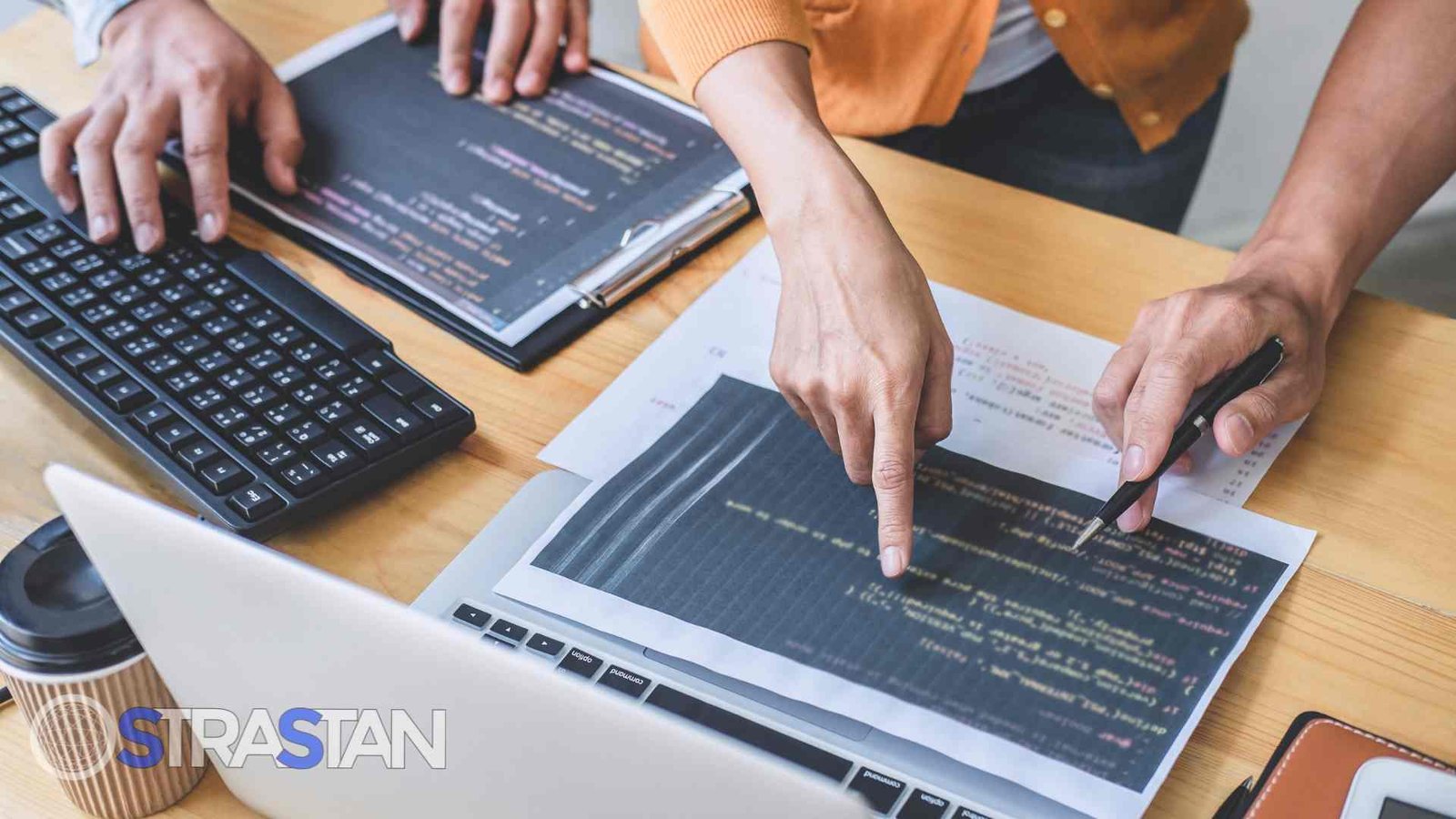 Two people pointing at code on a laptop, symbolizing the coding and collaboration stages of the dev lifecycle.